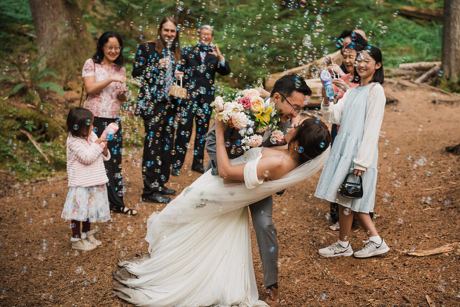 Groom dips bride for a kiss after their Mt Rainier forest wedding ceremony. 