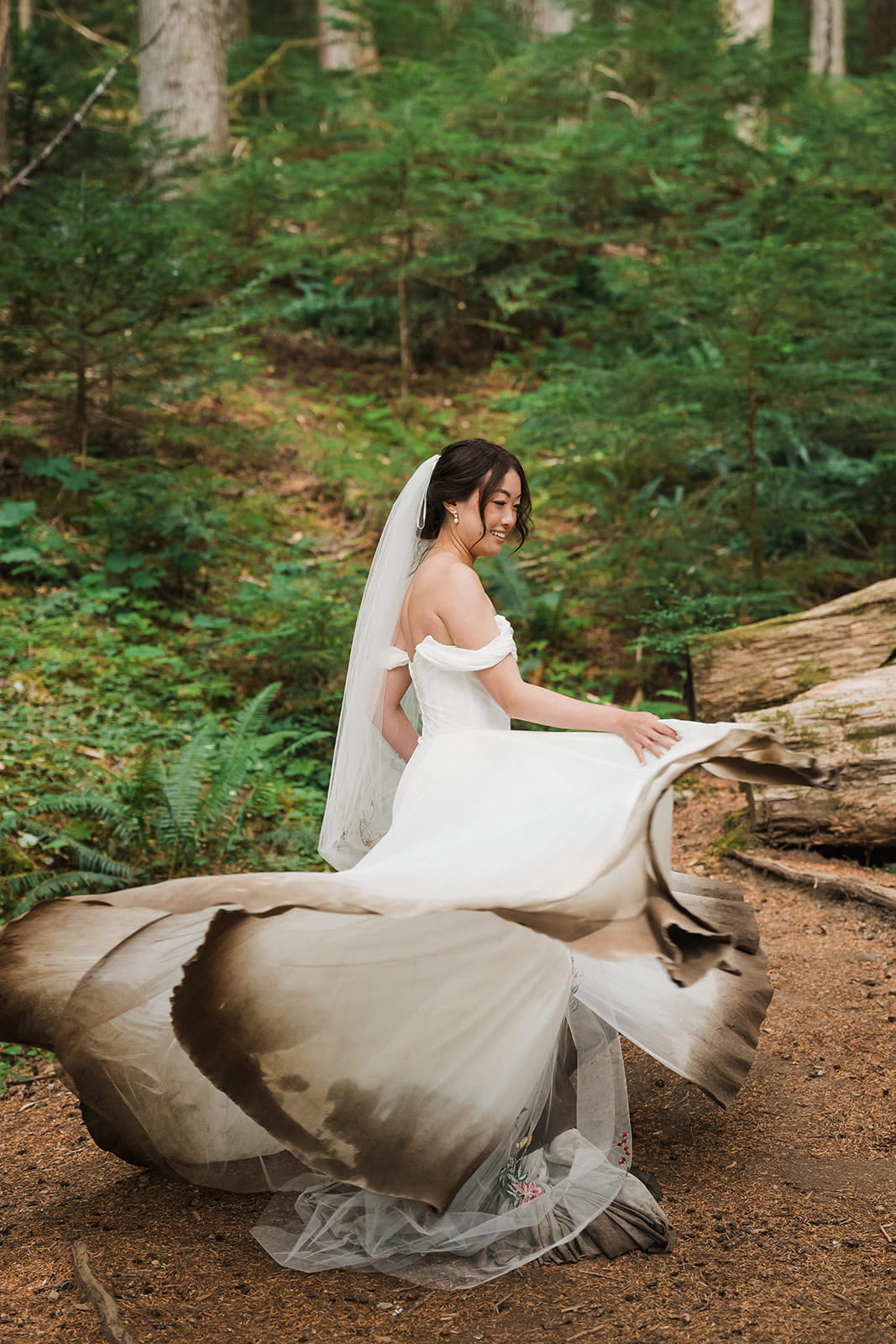Bride twirls in a muddy wedding dress in a forest clearing during her Washington wedding. 