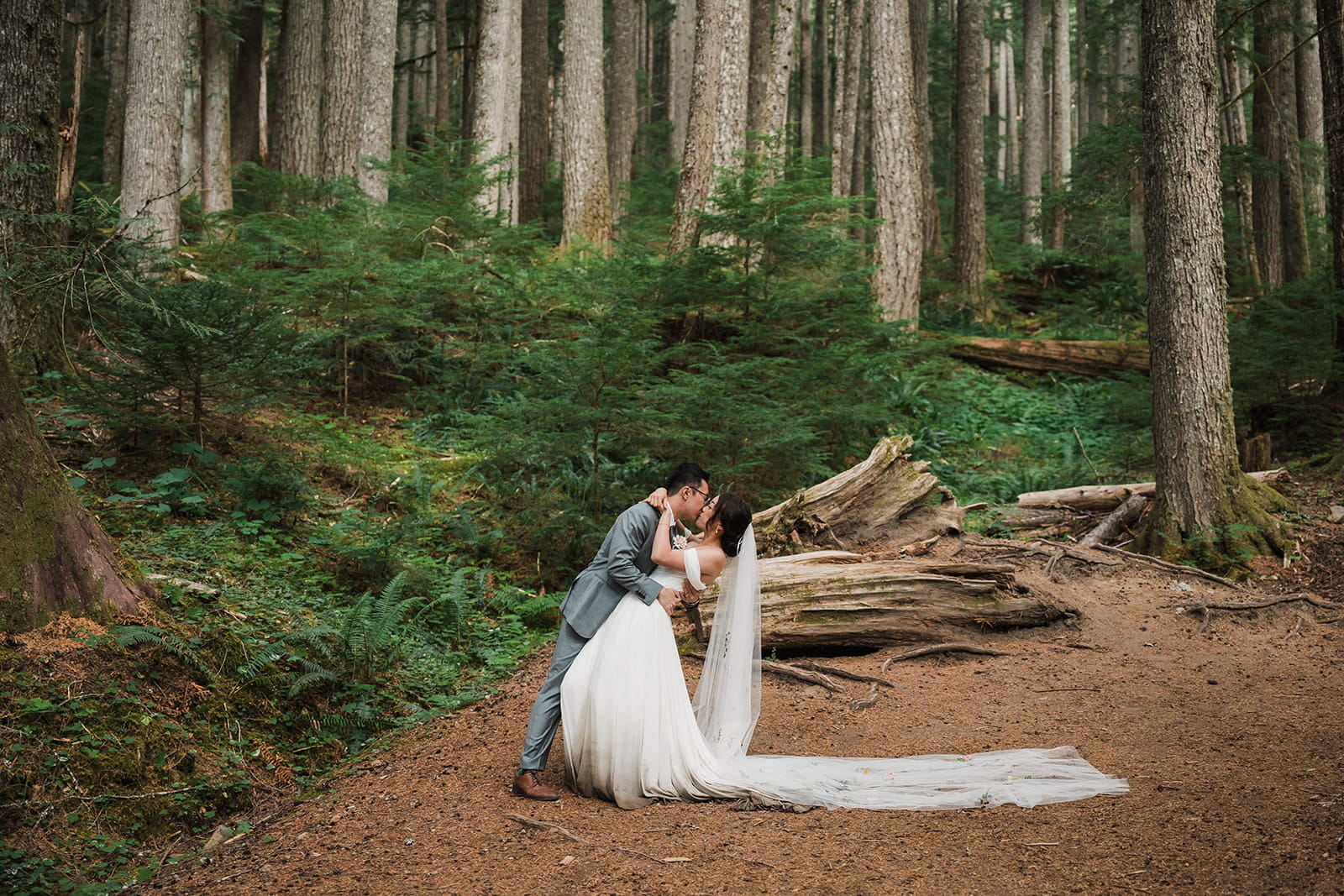 Bride and groom kiss in a forest clearing during their Mt Rainier wildflower and forest wedding. 