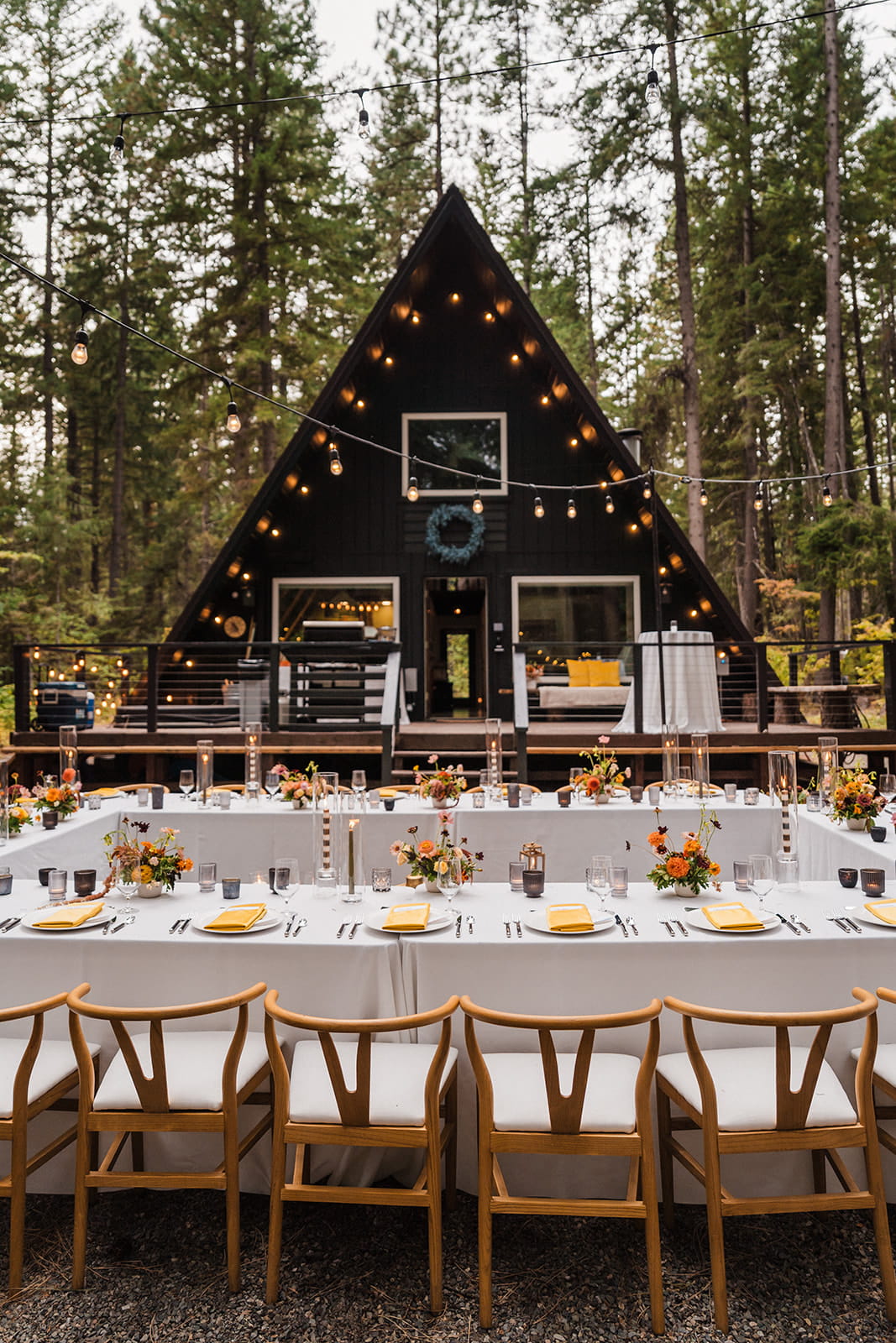 A-frame cabin micro wedding reception dinner with white tablecloth tables and wood chairs. 