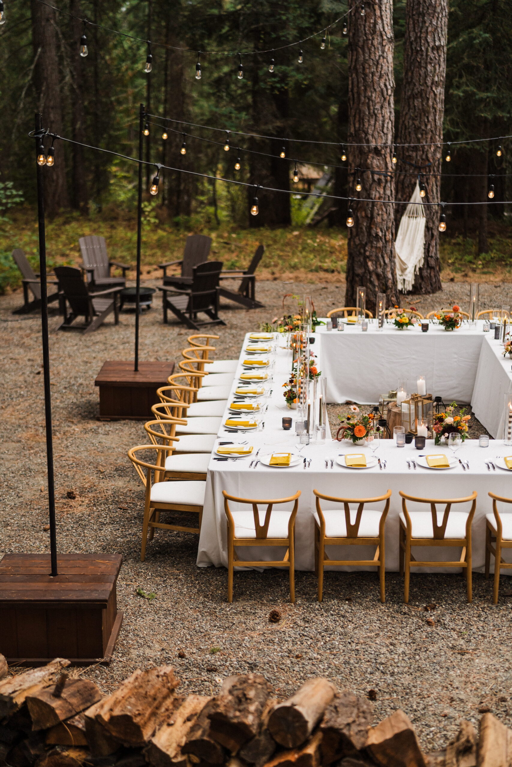 Square elopement reception tables sit under string lights outside a Washington cabin. 