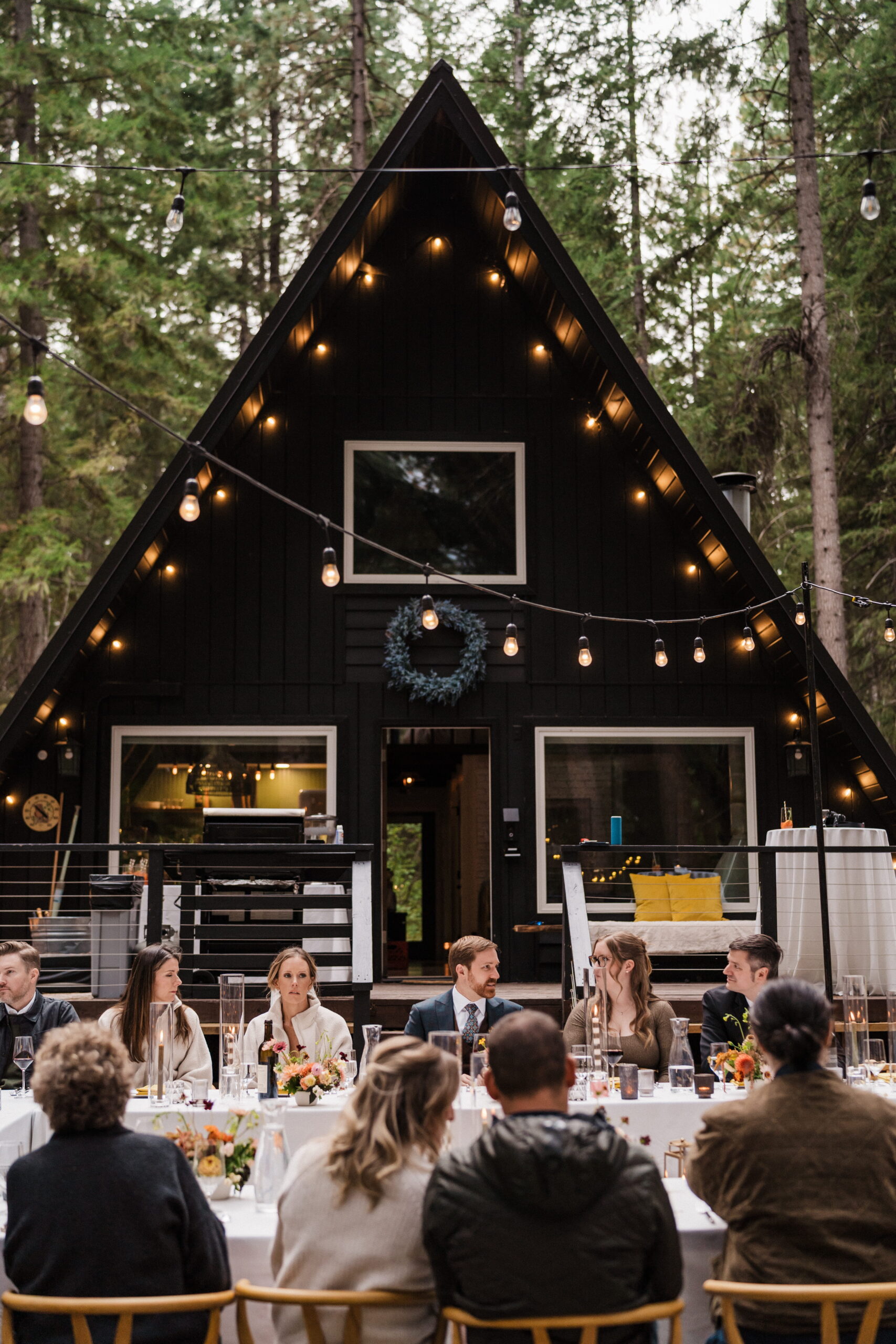 Guests sit in front of an A-frame cabin during an intimate wedding dinner in Washington. 