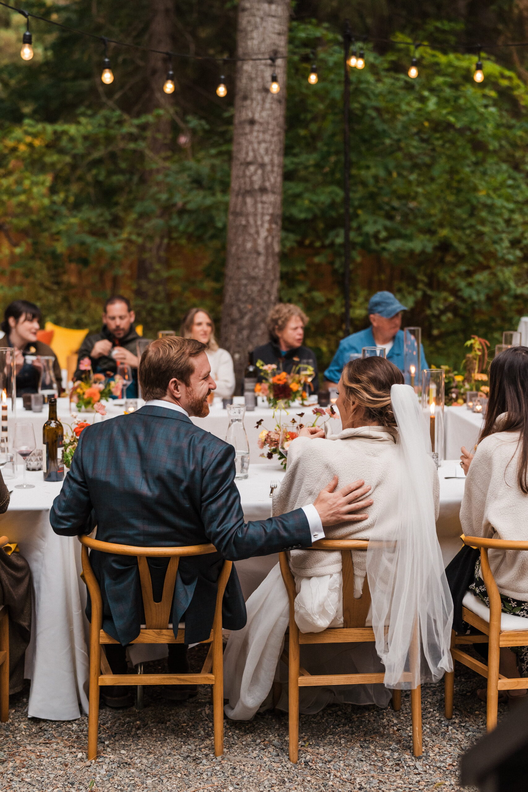 Bride and groom laugh while mingling with guests at their outdoor intimate wedding reception. 