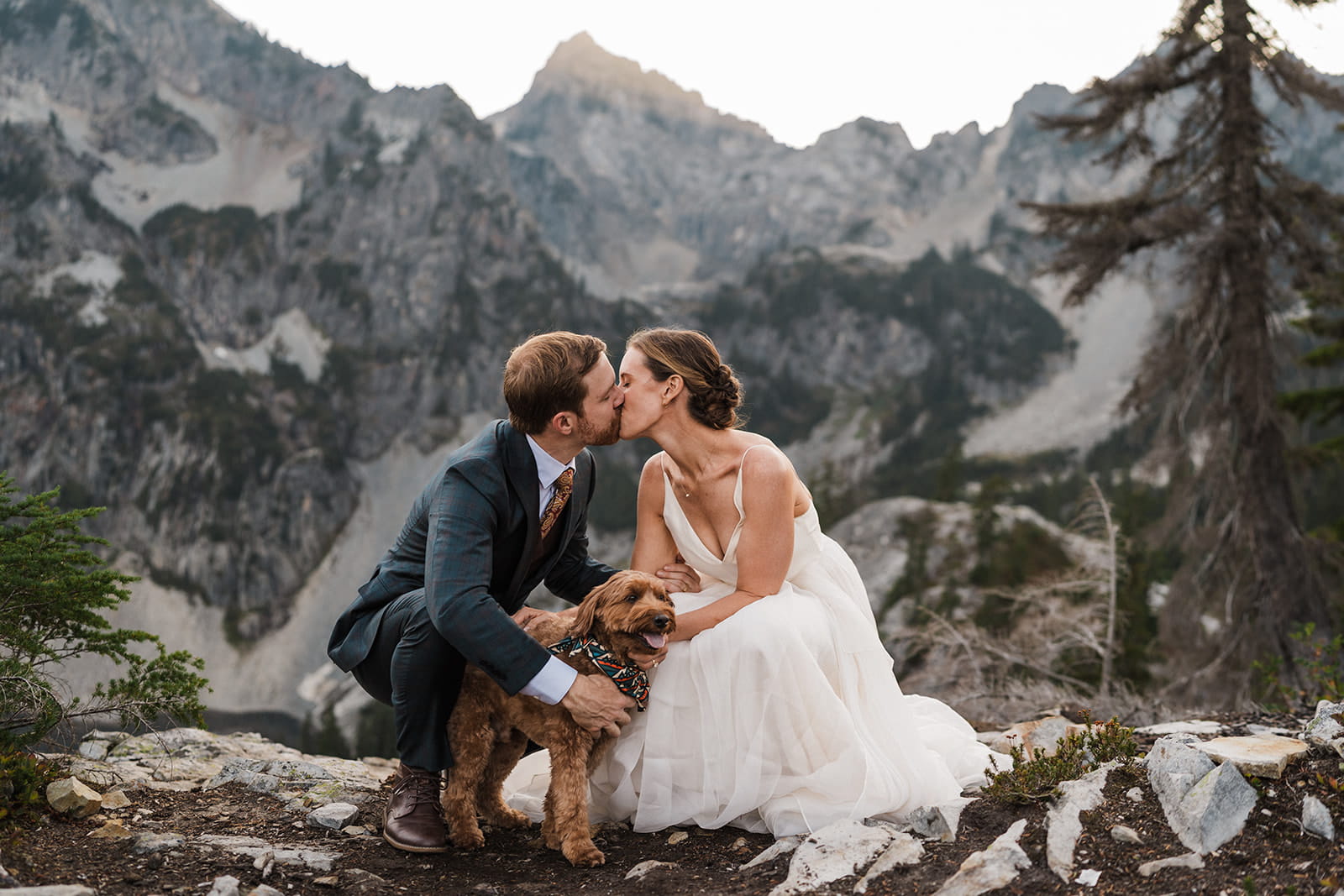 Newlyweds kiss during their backpacking wedding portraits with their dog. 
