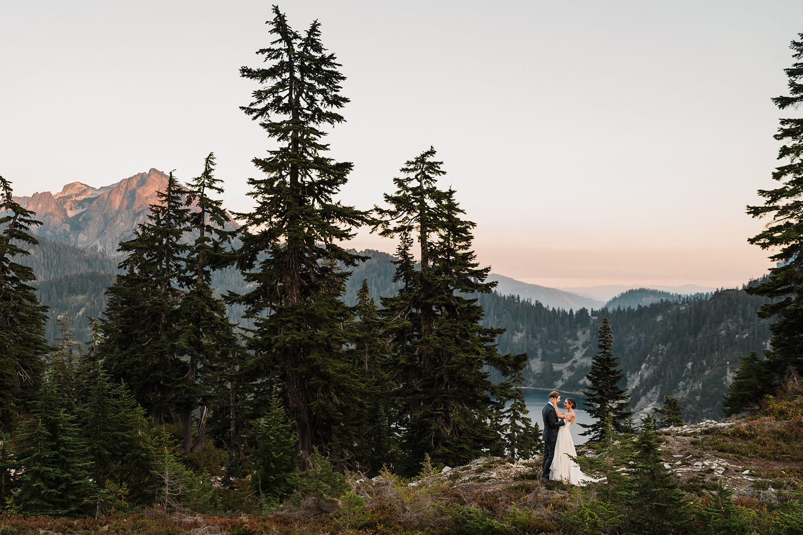 Couple dances on a mountain trail at sunset during their backpacking elopement. 