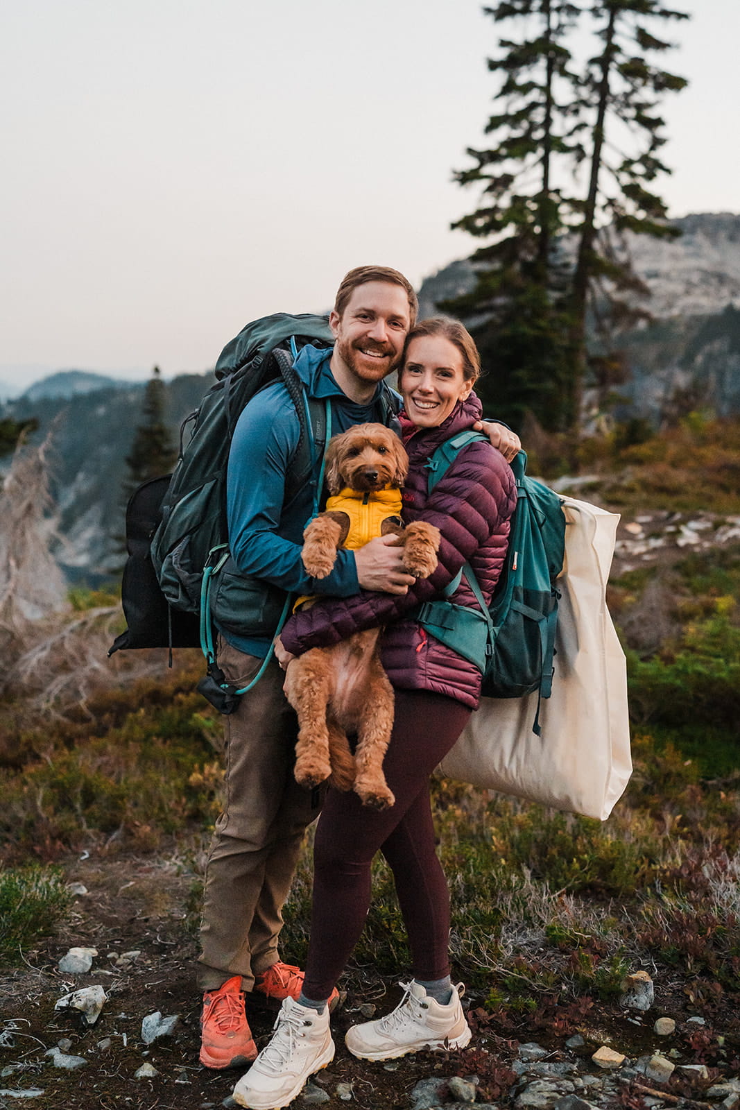 Couple holds their pup while hiking during their mountain elopement. 