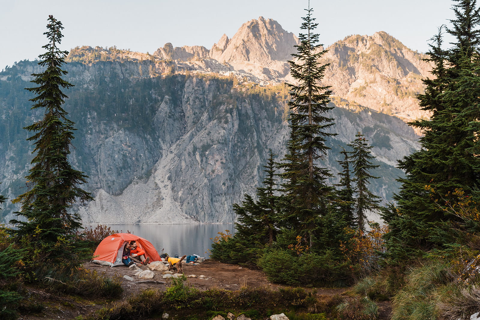 Couple sits at their tent during sunrise on Snow Lake Trail.