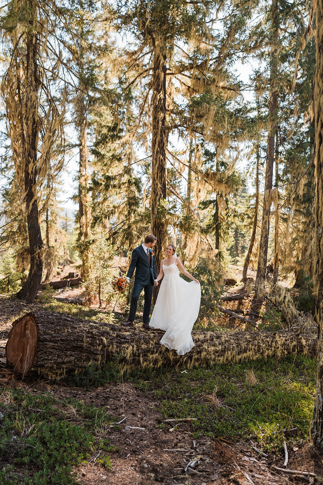 Bride lifts her dress during newlywed forest wedding photos in Washington. 