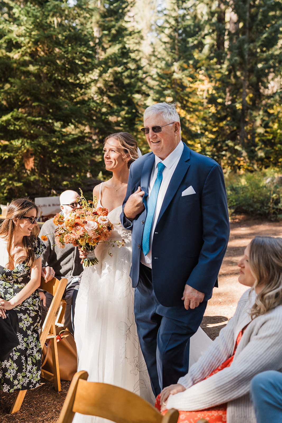 Bride walks down an outdoor wedding aisle with her father during her Washington forest wedding. 