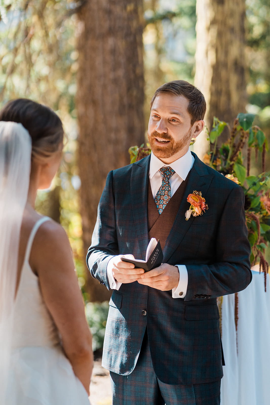 Groom reads wedding vows during an outdoor forest ceremony by Cooper Lake. 
