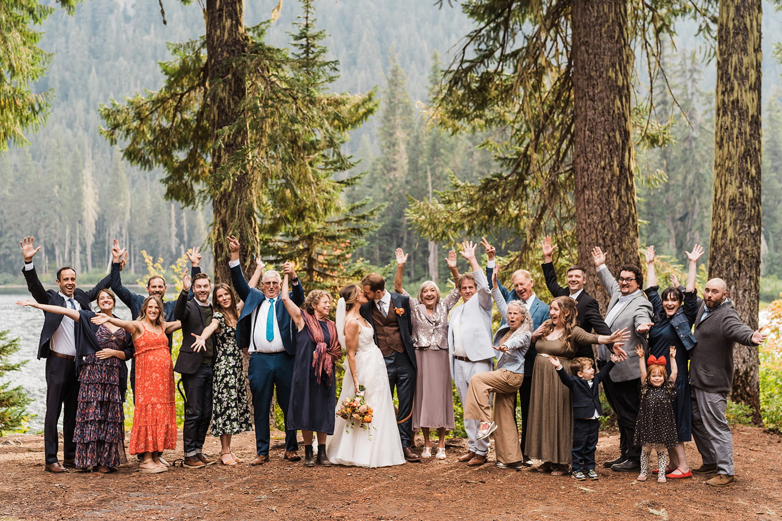 Bride and groom kiss while guests cheer at their Cooper Lake wedding ceremony. 