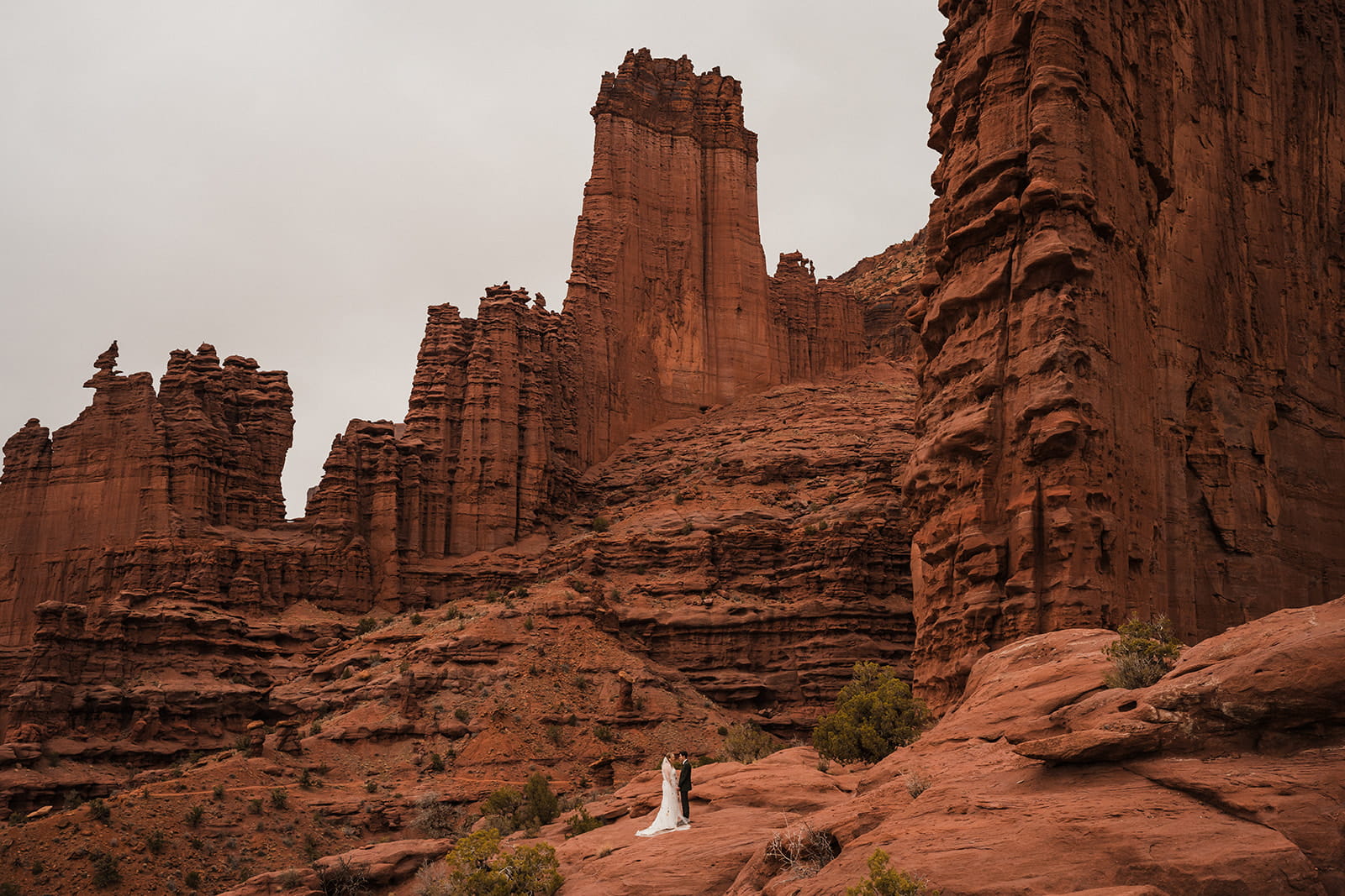 Newlyweds stand on a red rock trail in Moab, Utah during the adventure portion of their two-day elopement package.