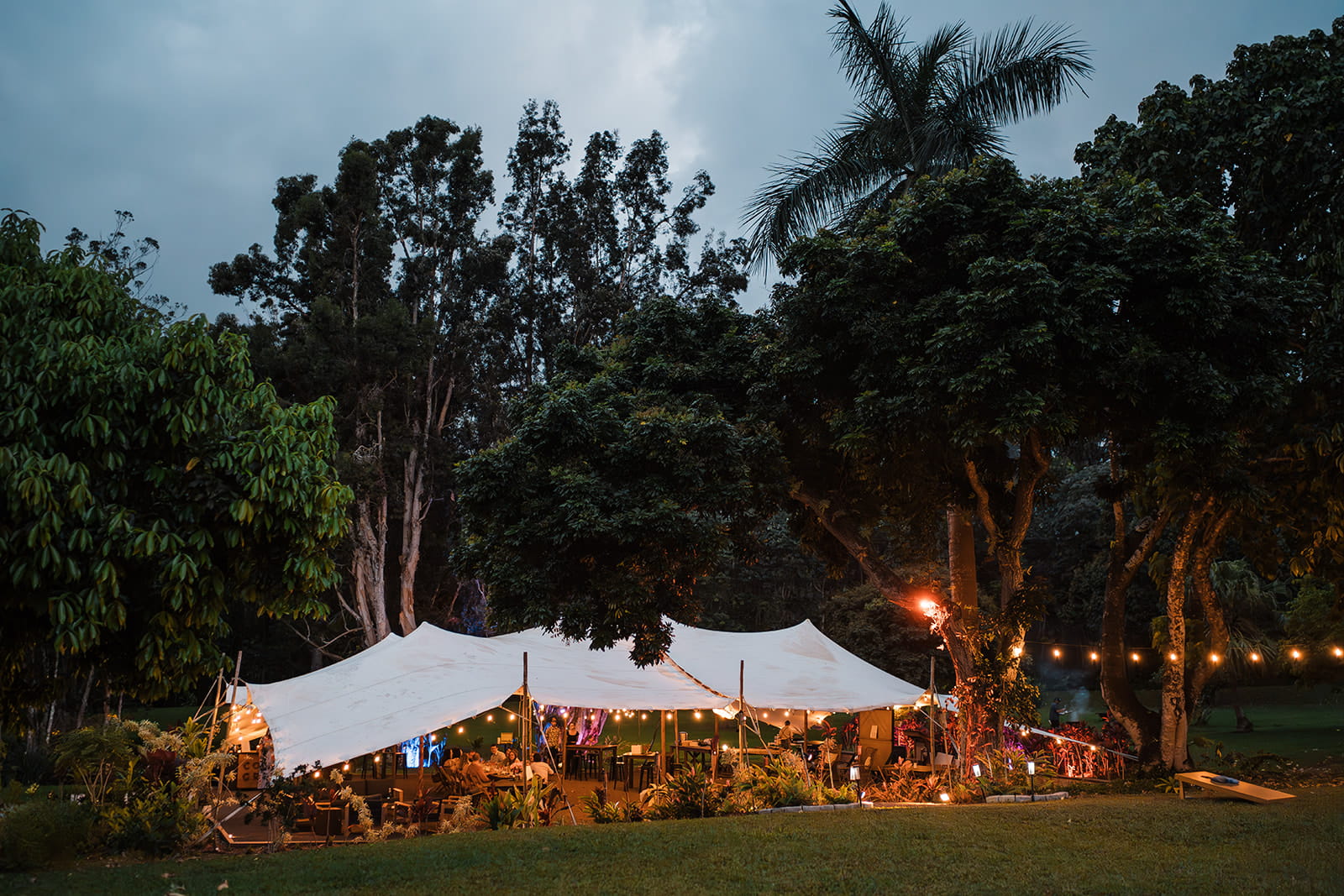 Guests sit under a white tent at Common Ground, a micro wedding venue in Kauai.