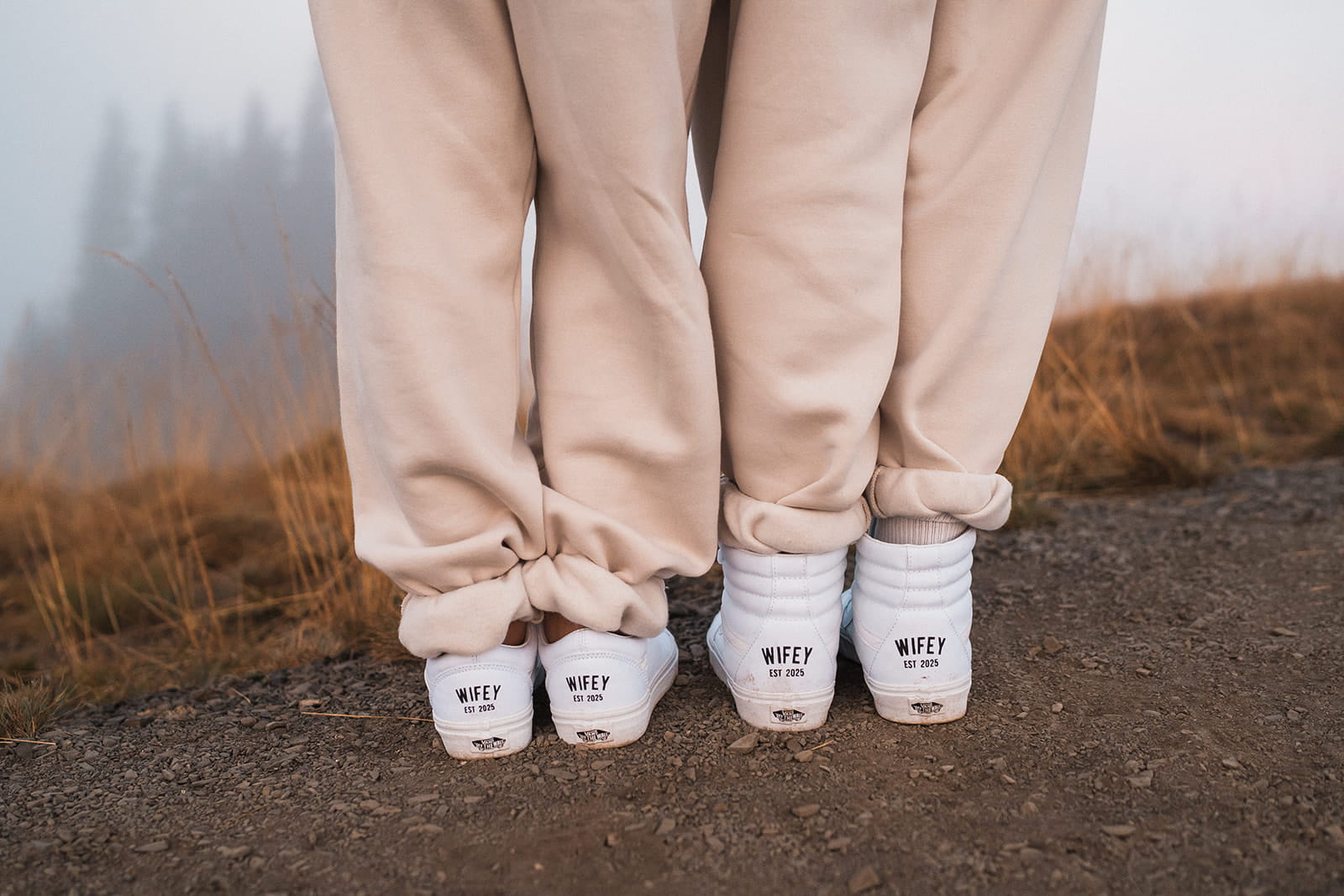 Two women in matching white sweatsuits and sneakers.