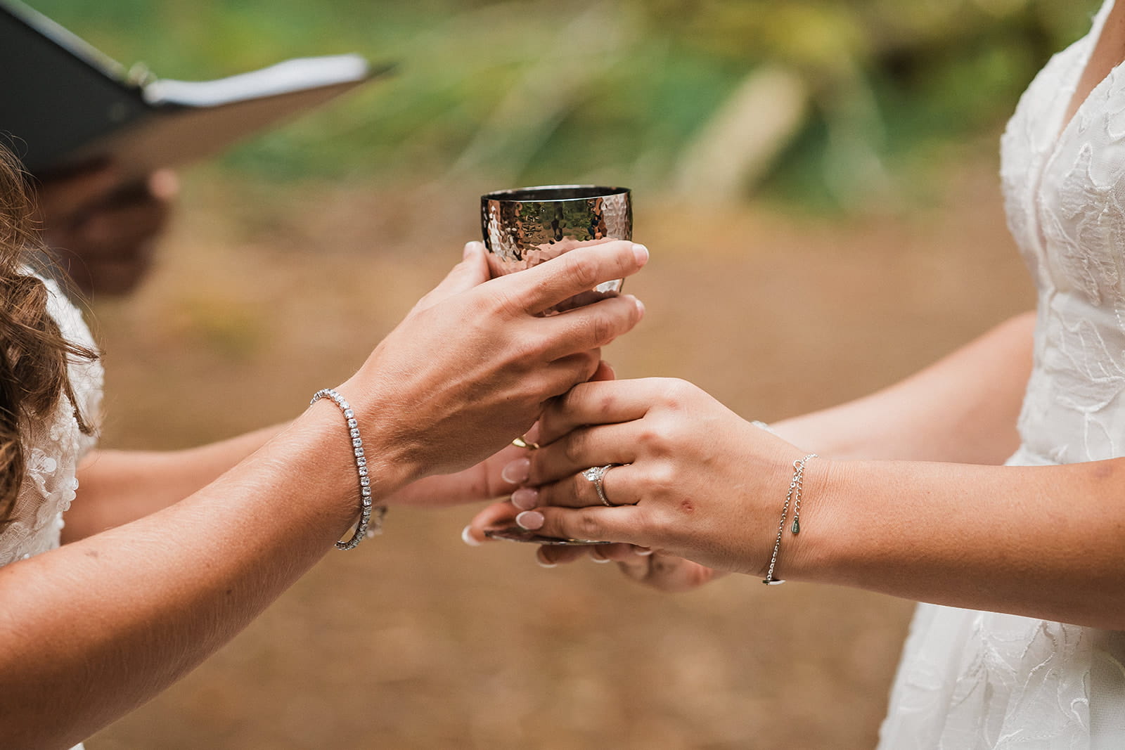 Two brides hold a wine glass during their Port Angeles forest wedding ceremony.