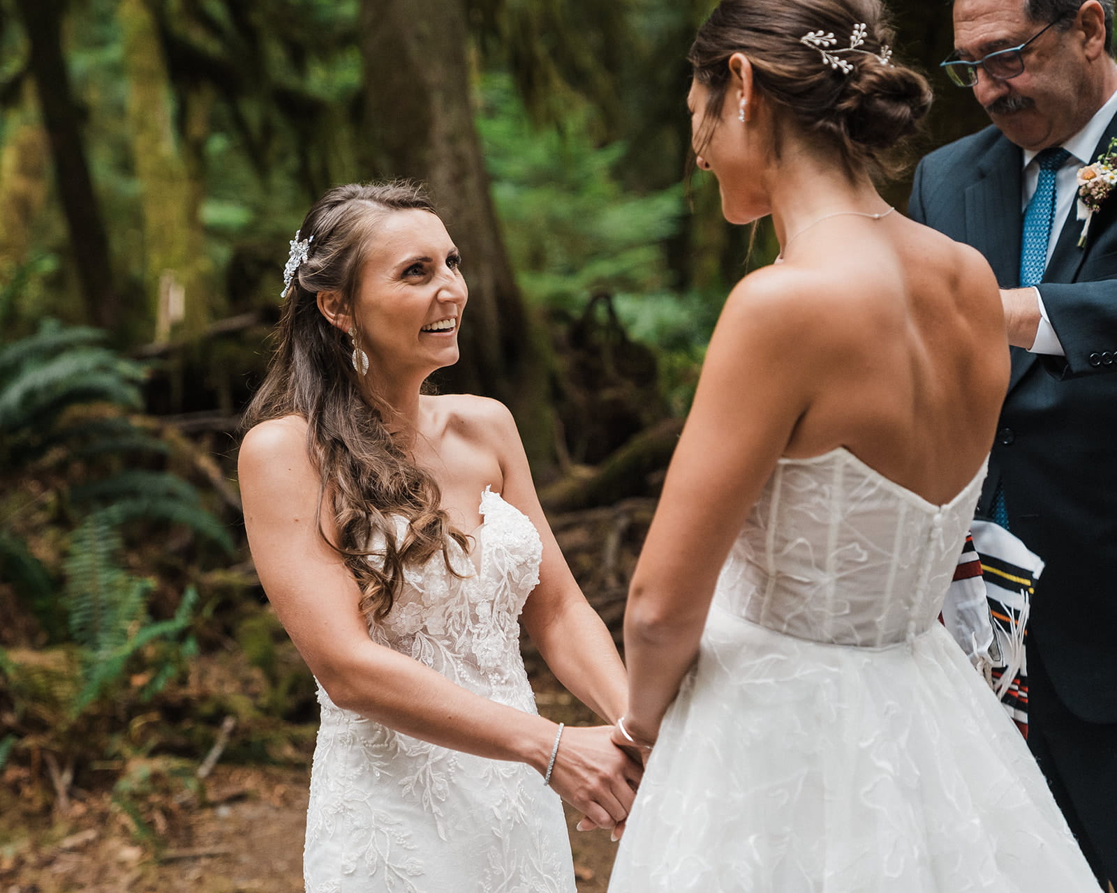Brides hold hands during their Port Angeles wedding in the forest.