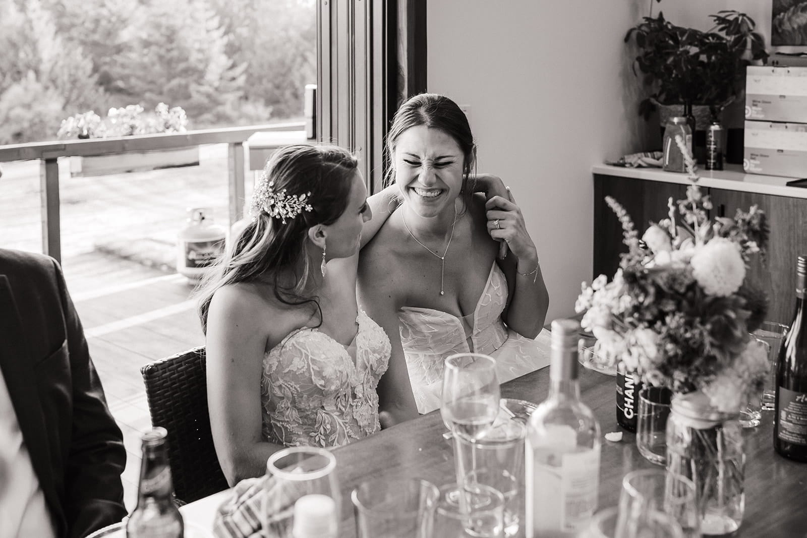 Brides laugh during their micro wedding dinner with family in Port Angeles. 