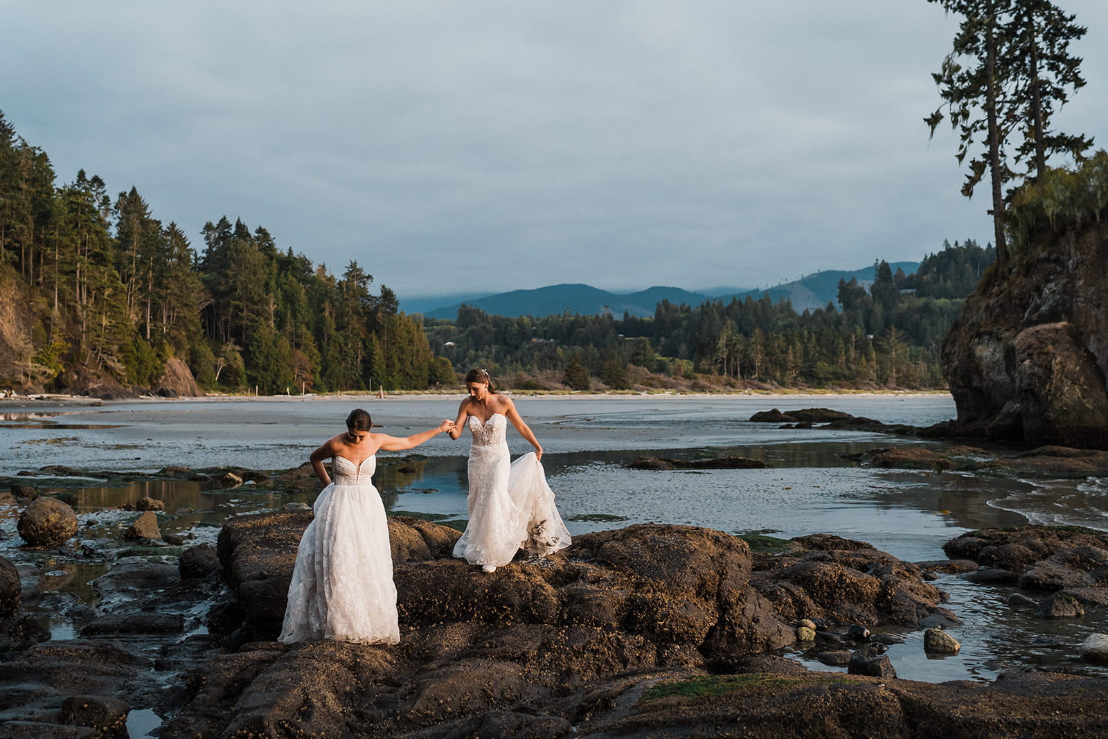 Brides hold hands on a rocky Washington beach on the Olympic Coast.