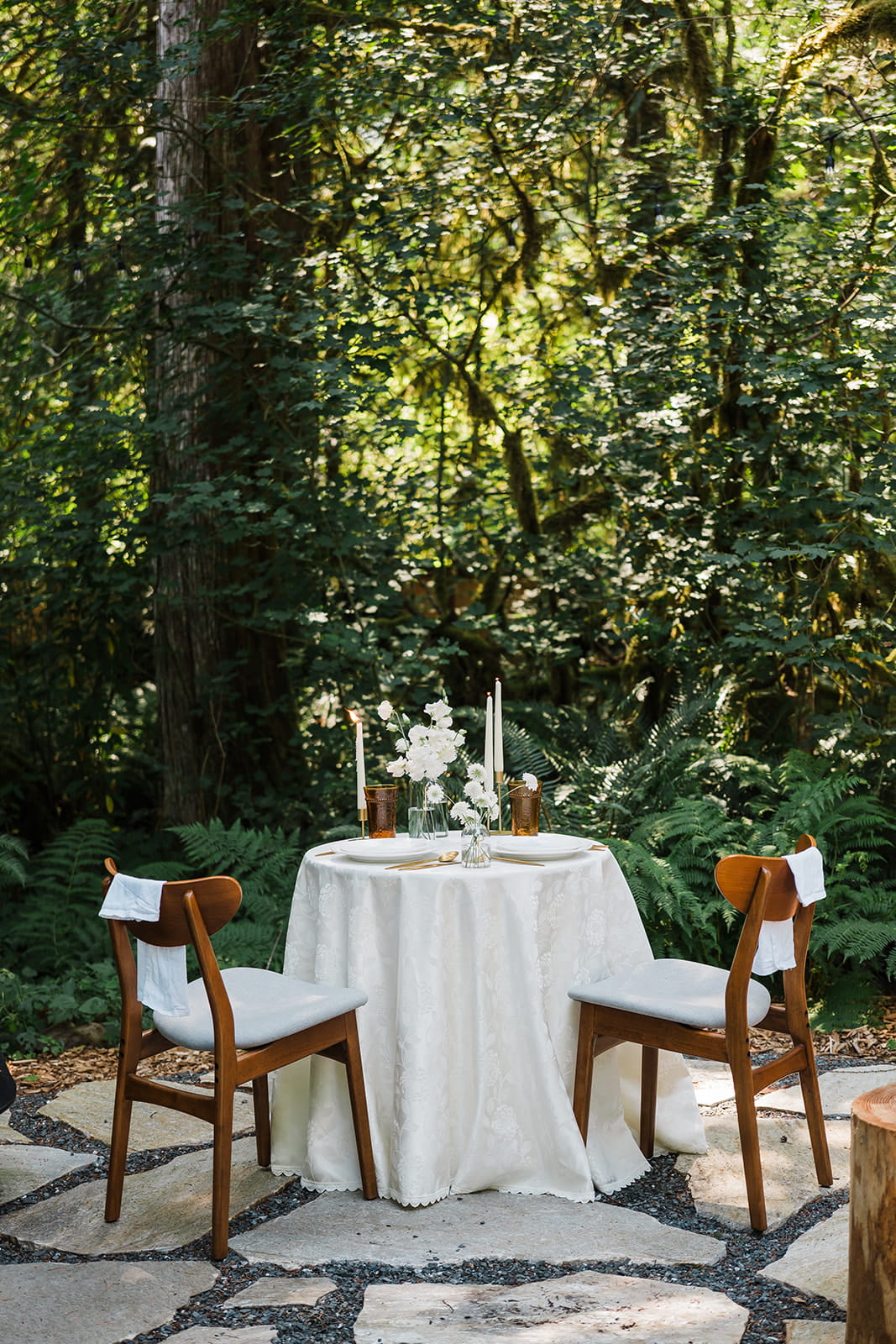 Round bistro table in the forest set for an intimate elopement dinner for two.